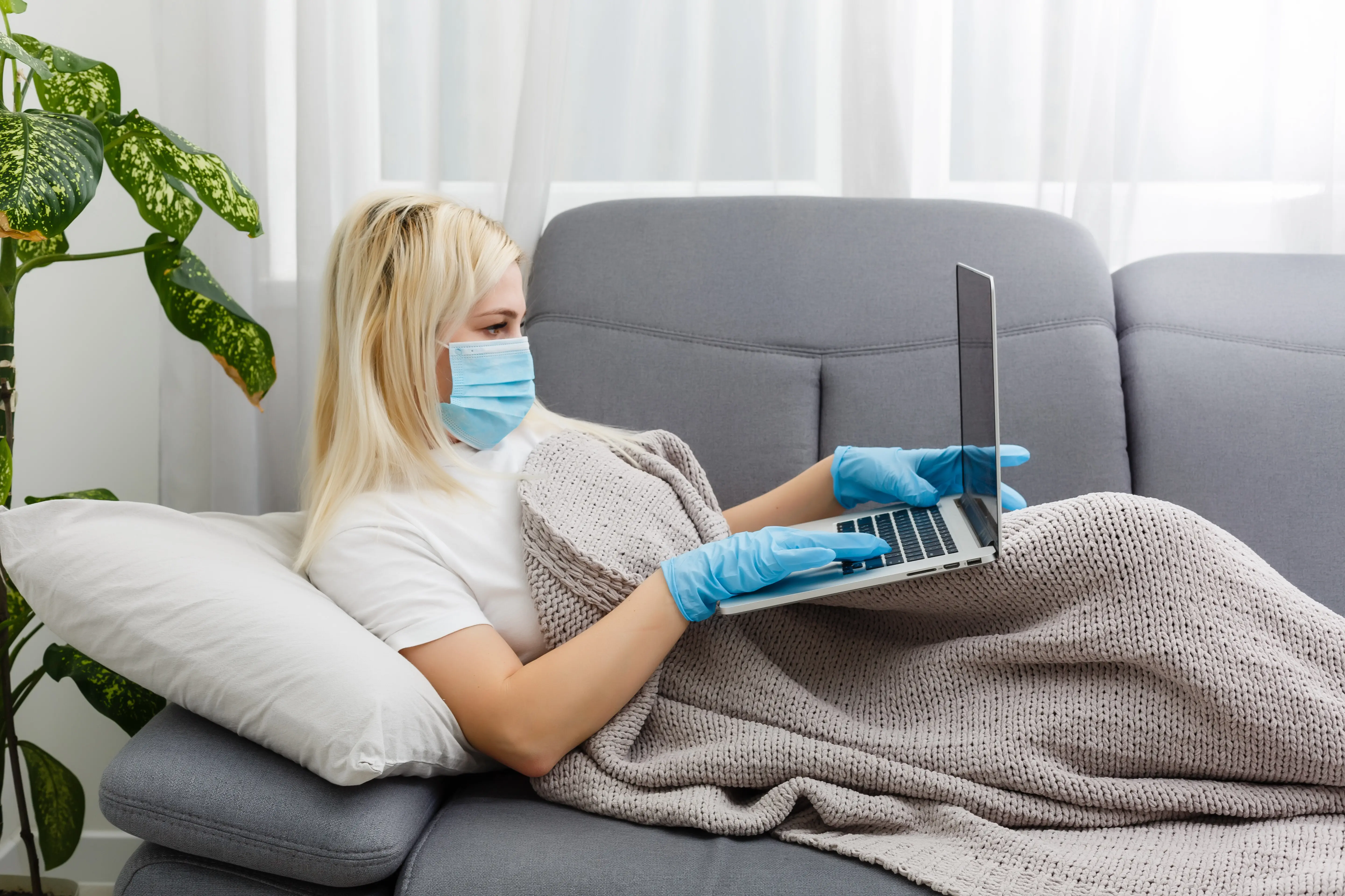 Coronavirus. Eine junge Geschäftsfrau arbeitet von zu Hause aus und trägt eine Schutzmaske. Die Geschäftsfrau ist wegen des Coronavirus in Quarantäne und trägt eine Schutzmaske. Arbeit von zu Hause.