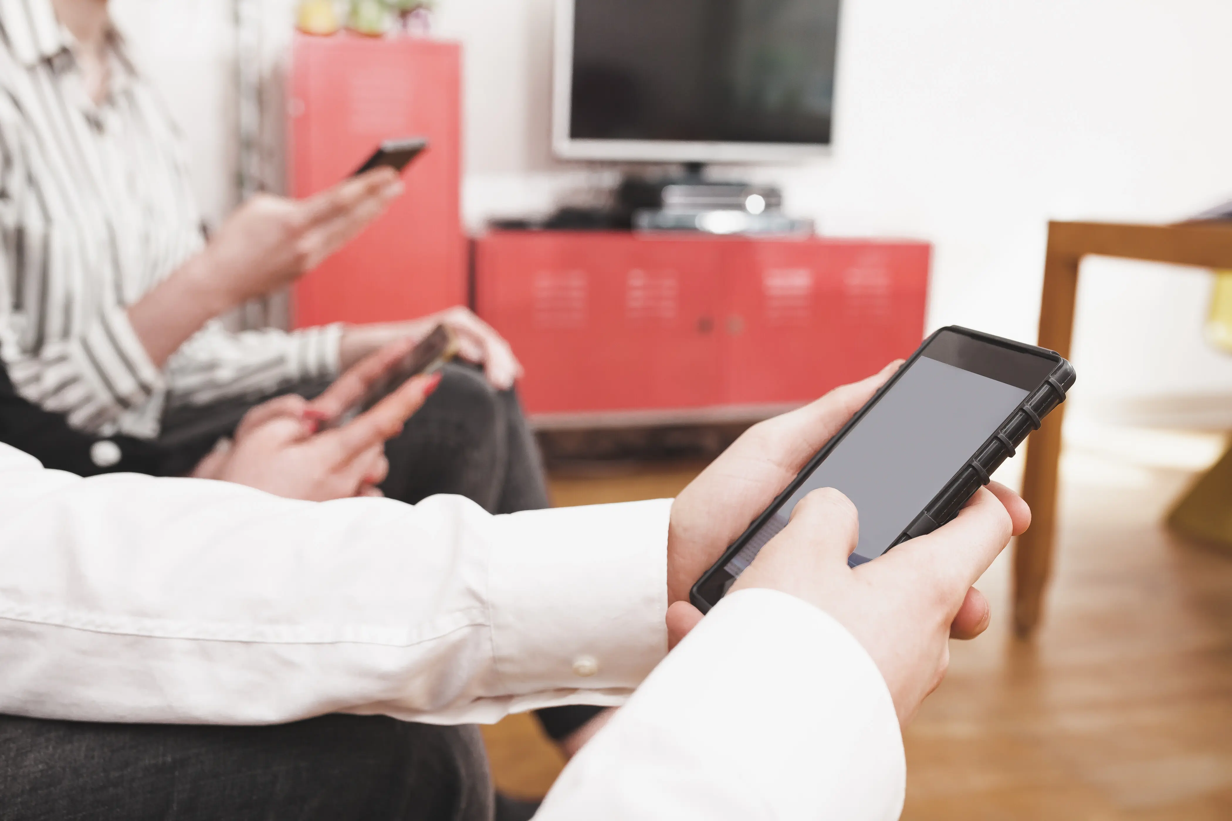 Mittlere Körperpartie von Personen, die Mobiltelefone benutzen.